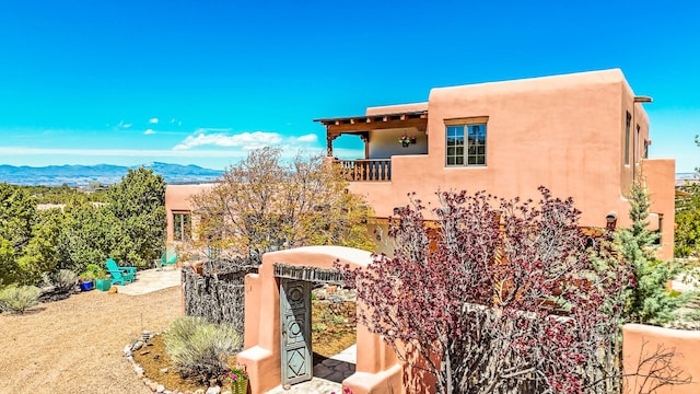 exterior space featuring a mountain view, stucco siding, and a balcony