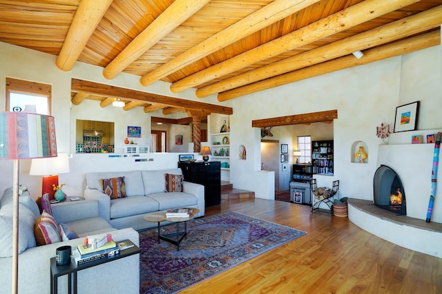 living area featuring a large fireplace, beam ceiling, wood ceiling, and wood finished floors