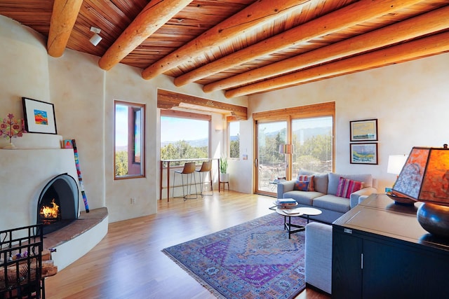 living room featuring light wood-style floors, a lit fireplace, beam ceiling, and wooden ceiling