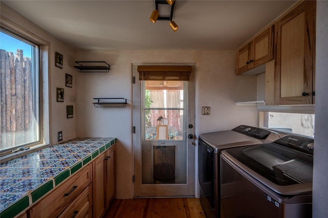 laundry area featuring cabinet space, wood finished floors, and washer and dryer