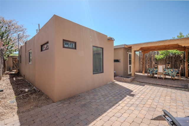 back of property with fence, stucco siding, and a patio area