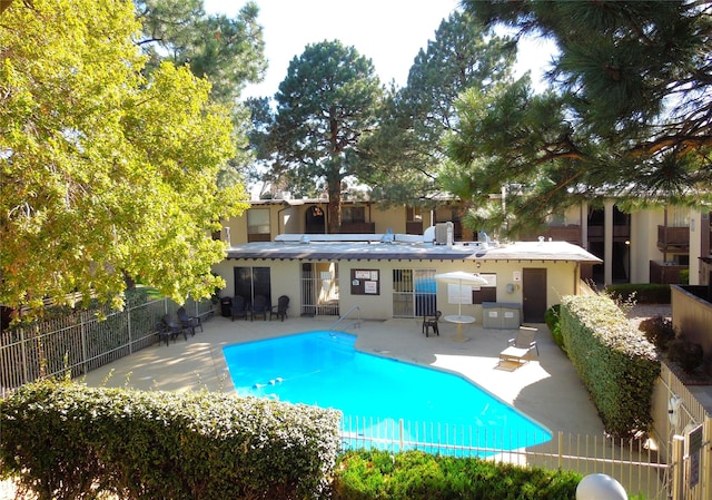 back of property with a community pool, a patio, fence, and stucco siding