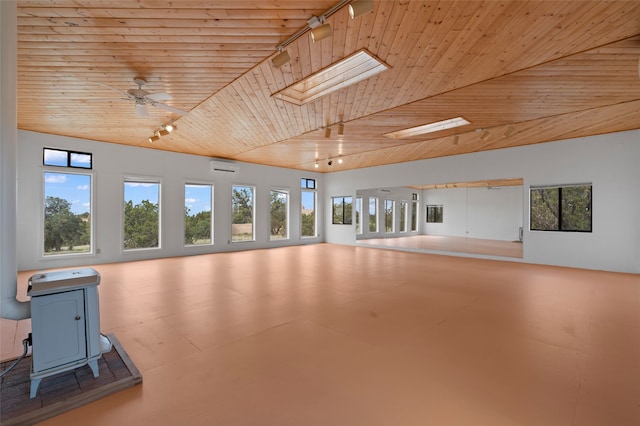 1 Jornada Loop, Santa Fe, NM 87508 - unfurnished living room featuring rail lighting, wood ceiling, a wood stove, a ceiling fan, and a wall unit AC