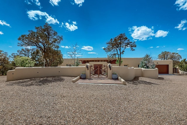 rear view of house with a gate, stucco siding, and fence private yard