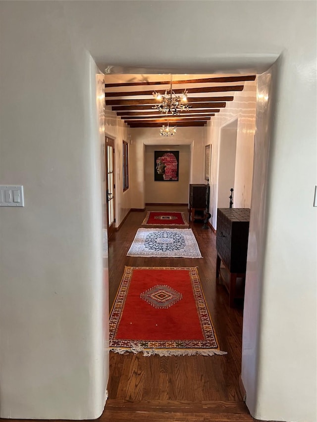 hallway with an inviting chandelier, beamed ceiling, and wood finished floors
