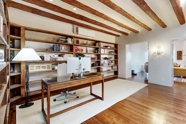office area featuring wood finished floors, built in study area, a wall mounted AC, and beam ceiling