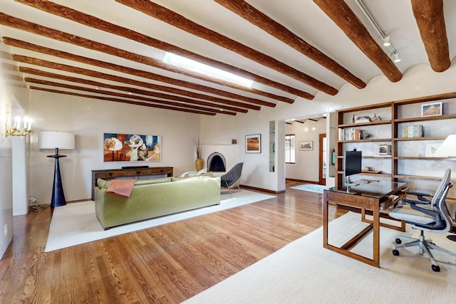 home office with baseboards, beam ceiling, rail lighting, and wood finished floors