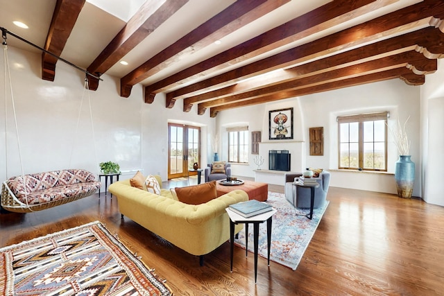 living area with plenty of natural light, beamed ceiling, and wood finished floors