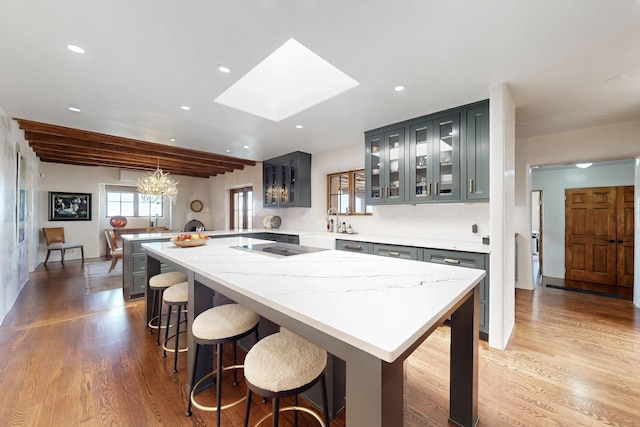 kitchen with a peninsula, glass insert cabinets, recessed lighting, a notable chandelier, and a skylight