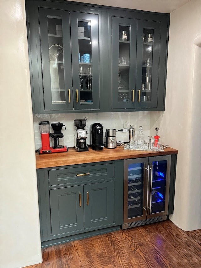 bar with wine cooler, backsplash, dark wood finished floors, and wet bar