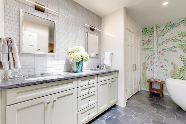 full bath with a freestanding bath, a sink, tile patterned flooring, double vanity, and decorative backsplash