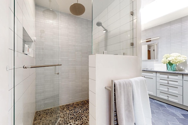 bathroom with vanity, tiled shower, and tile walls