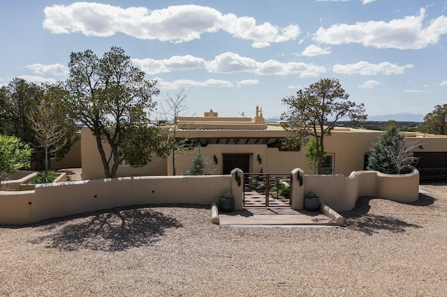 back of property featuring a gate, a fenced front yard, stucco siding, and a chimney