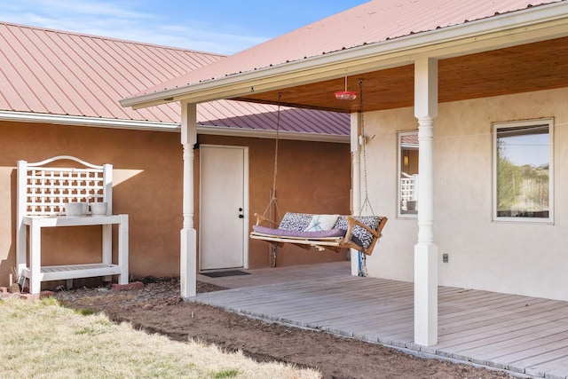 doorway to property featuring a deck, metal roof, and stucco siding