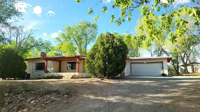 view of front of home featuring an attached garage, driveway, a chimney, and stucco siding
