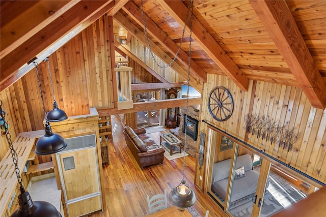 living area featuring a stone fireplace, wood walls, and hardwood / wood-style floors