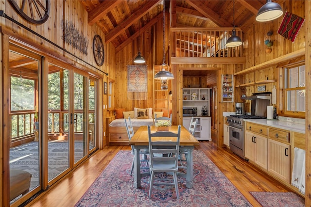 kitchen with appliances with stainless steel finishes, beam ceiling, high vaulted ceiling, wood walls, and wooden ceiling