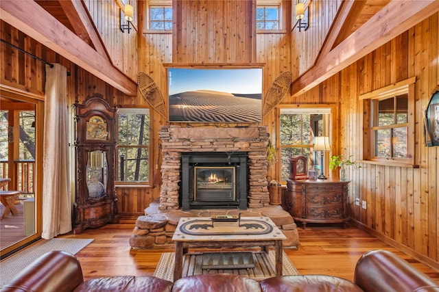 living area with wood walls, a high ceiling, hardwood / wood-style floors, and a fireplace