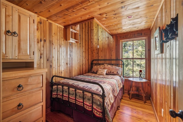 bedroom with light wood-style flooring, wooden walls, and wood ceiling