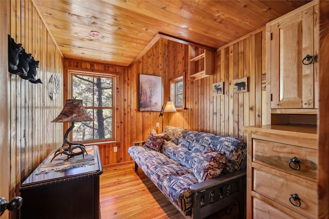 living area featuring wood ceiling, wood walls, and light wood finished floors