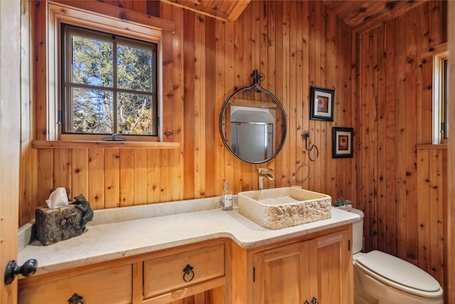 bathroom with vanity, toilet, and wood walls