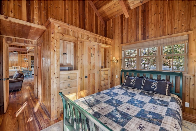 bedroom with wood walls, lofted ceiling, wood finished floors, and wooden ceiling
