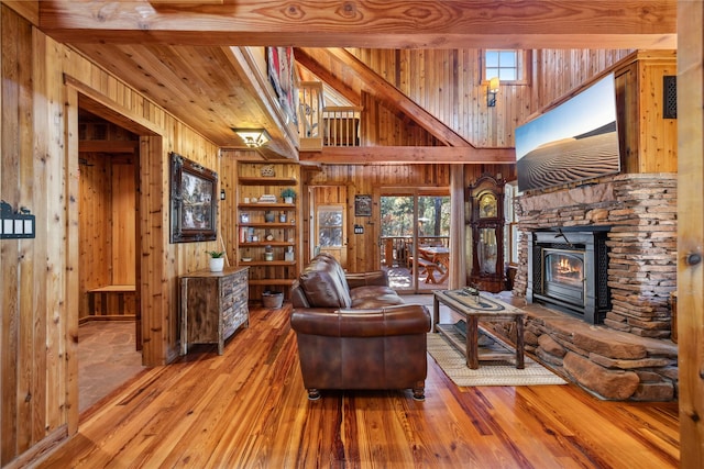 living room featuring wooden walls, a lit fireplace, plenty of natural light, and hardwood / wood-style flooring