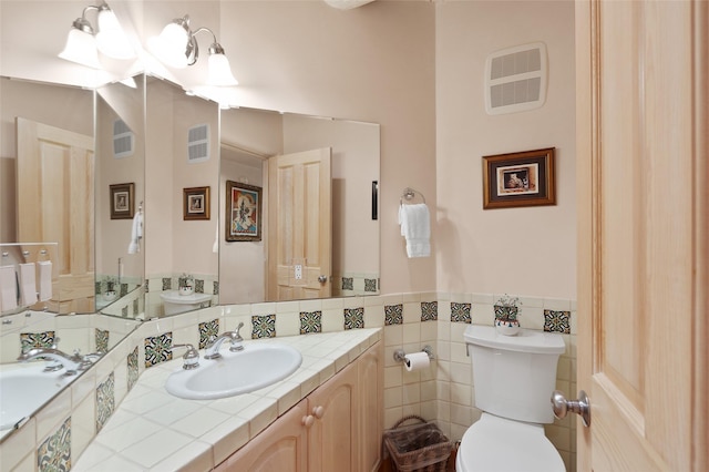 3101 Old Pecos Trl Unit 627, Santa Fe, NM 87505 - bathroom with toilet, tile walls, a wainscoted wall, vanity, and visible vents
