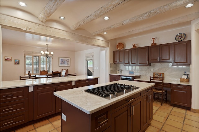 3101 Old Pecos Trl Unit 627, Santa Fe, NM 87505 - kitchen with stainless steel gas cooktop, an inviting chandelier, beamed ceiling, a center island, and decorative backsplash