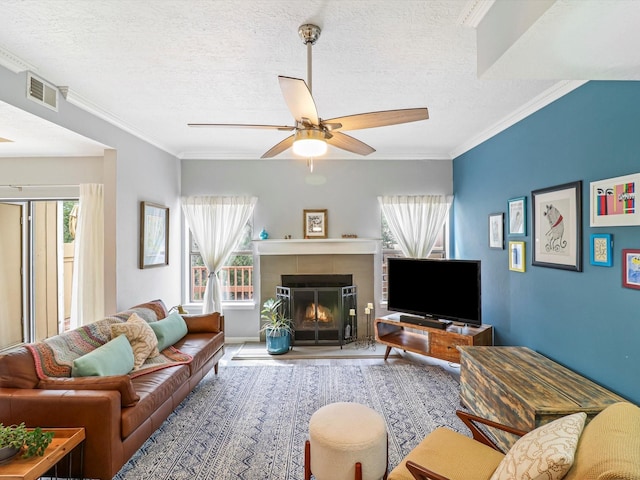 505 Oppenheimer Dr Unit 1304, Los Alamos, NM 87544 - living room with visible vents, crown molding, a textured ceiling, a tile fireplace, and a ceiling fan