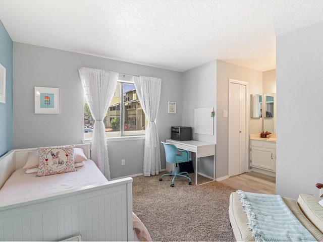 505 Oppenheimer Dr Unit 1304, Los Alamos, NM 87544 - bedroom featuring a textured ceiling, baseboards, light carpet, and ensuite bathroom