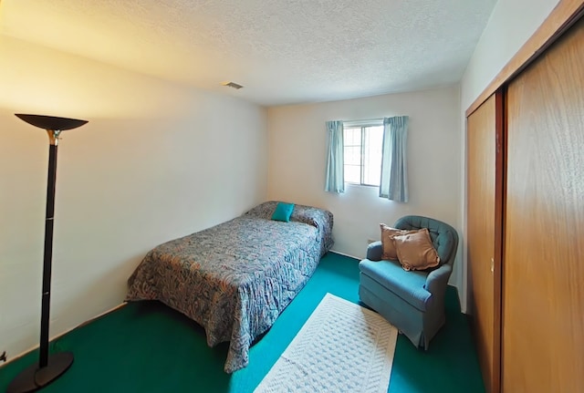 carpeted bedroom with a closet, a textured ceiling, and visible vents