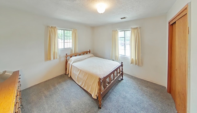carpeted bedroom featuring visible vents, a textured ceiling, a closet, and multiple windows