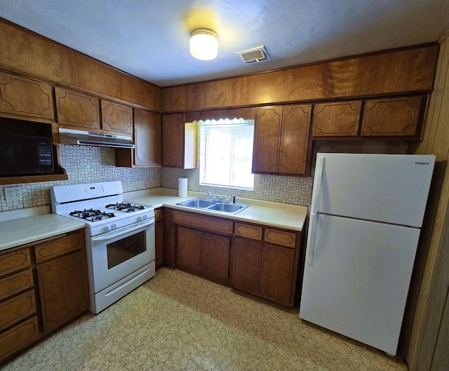 kitchen featuring a sink, backsplash, white appliances, and visible vents