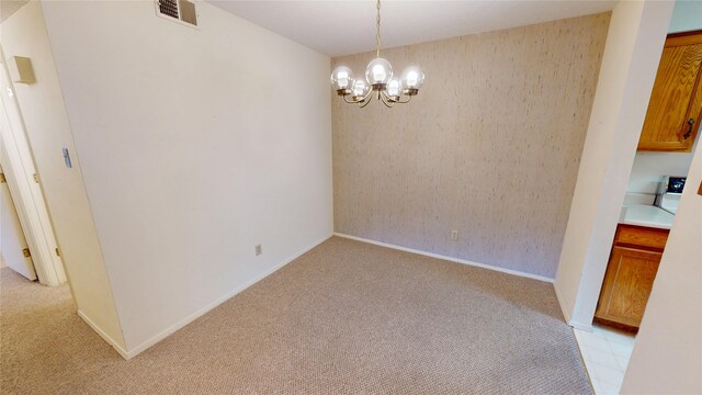 unfurnished dining area with baseboards, visible vents, light carpet, and an inviting chandelier
