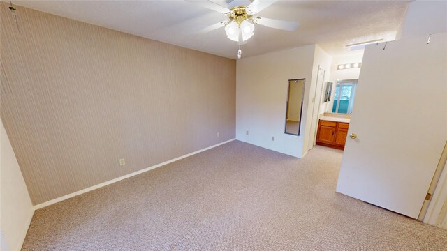 unfurnished room featuring a ceiling fan, baseboards, and light colored carpet