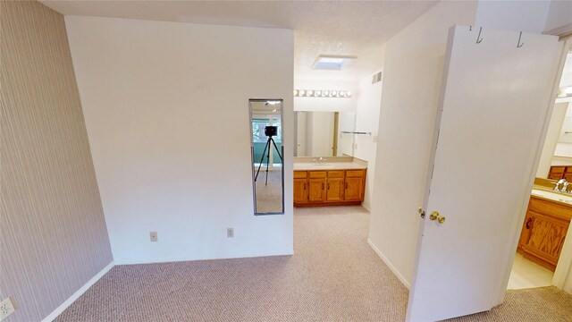 corridor featuring a sink and light colored carpet