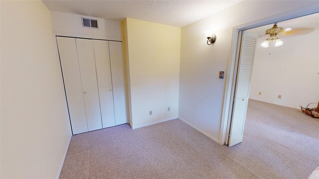 unfurnished bedroom featuring visible vents, carpet, baseboards, and a closet