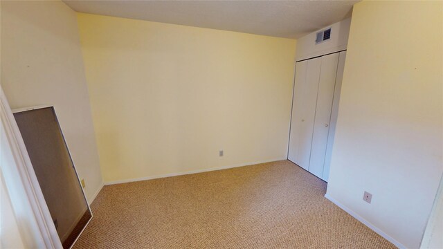 unfurnished bedroom with a closet, baseboards, light colored carpet, and visible vents