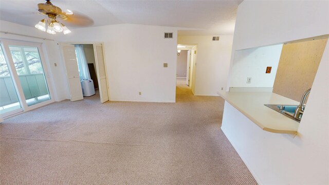 unfurnished living room with visible vents, a ceiling fan, a sink, and light carpet