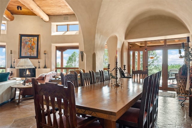 35 Sage Cir, Santa Fe, NM 87506 - dining area with wood ceiling, arched walkways, beamed ceiling, a high ceiling, and stone tile floors