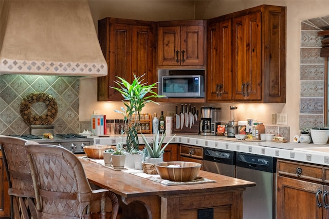 35 Sage Cir, Santa Fe, NM 87506 - kitchen featuring brown cabinetry, premium range hood, light countertops, appliances with stainless steel finishes, and backsplash