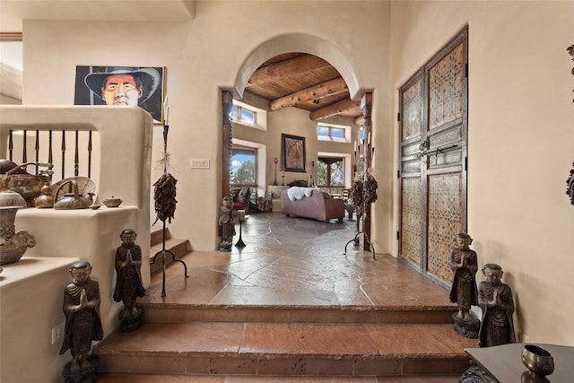 35 Sage Cir, Santa Fe, NM 87506 - foyer entrance with wood ceiling, a towering ceiling, arched walkways, beam ceiling, and stone tile floors