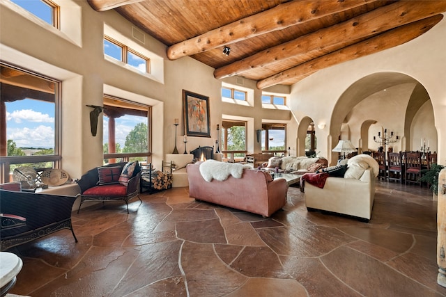 35 Sage Cir, Santa Fe, NM 87506 - living area with stone tile floors, beamed ceiling, a high ceiling, wooden ceiling, and arched walkways