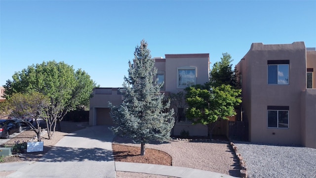 pueblo-style house with a garage, stucco siding, and driveway
