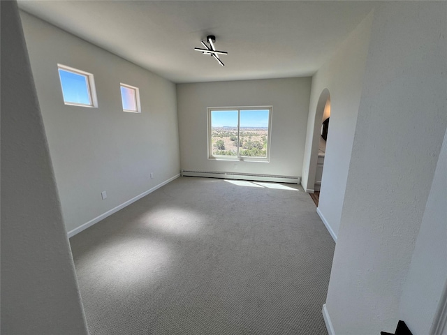 carpeted empty room featuring baseboards, arched walkways, and a baseboard radiator