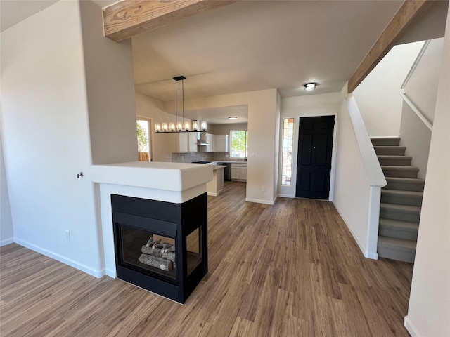 entrance foyer with baseboards, stairs, wood finished floors, and a multi sided fireplace