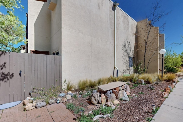 view of side of home with stucco siding and fence