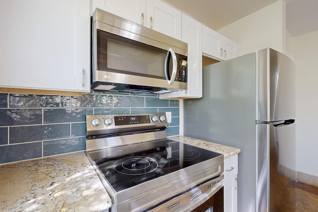 kitchen with appliances with stainless steel finishes, white cabinets, decorative backsplash, and light stone counters