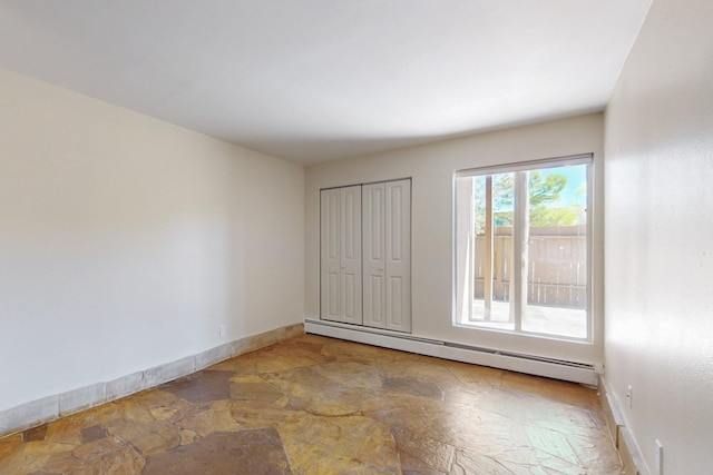 empty room with baseboards, stone finish flooring, and baseboard heating